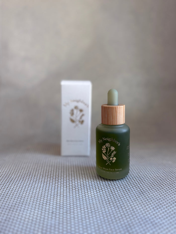 Green dropper bottle of My Neighbor's blue moon face serum and white packaging box in background.