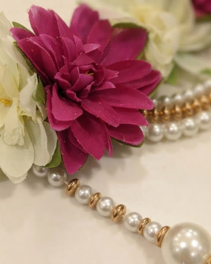 Close-up magenta flower on ivory petals with pearl and gold bead toran chain