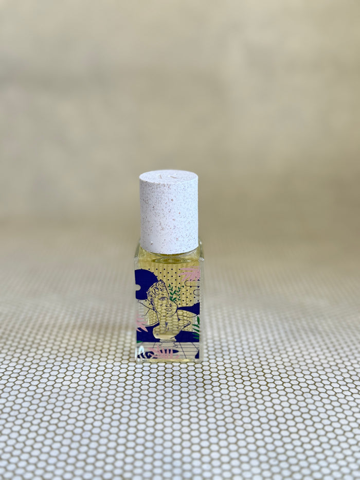 small glass bottle of maison matine perfume with greek bust graphic design on bottle.