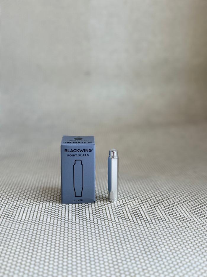 Blackwing product packaging and pen on a textured surface with a neutral background
