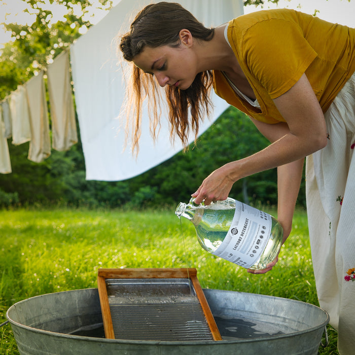 Woman pouring out of a Rustic Strength Laundry Detergent bottle