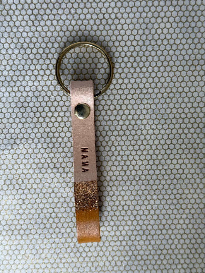 Leather rust colored keychain with 'MAMA' engraving on a textured surface