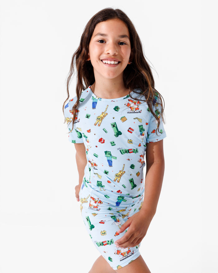 Young girl wearing a light blue pajama set with animal prints on a white background