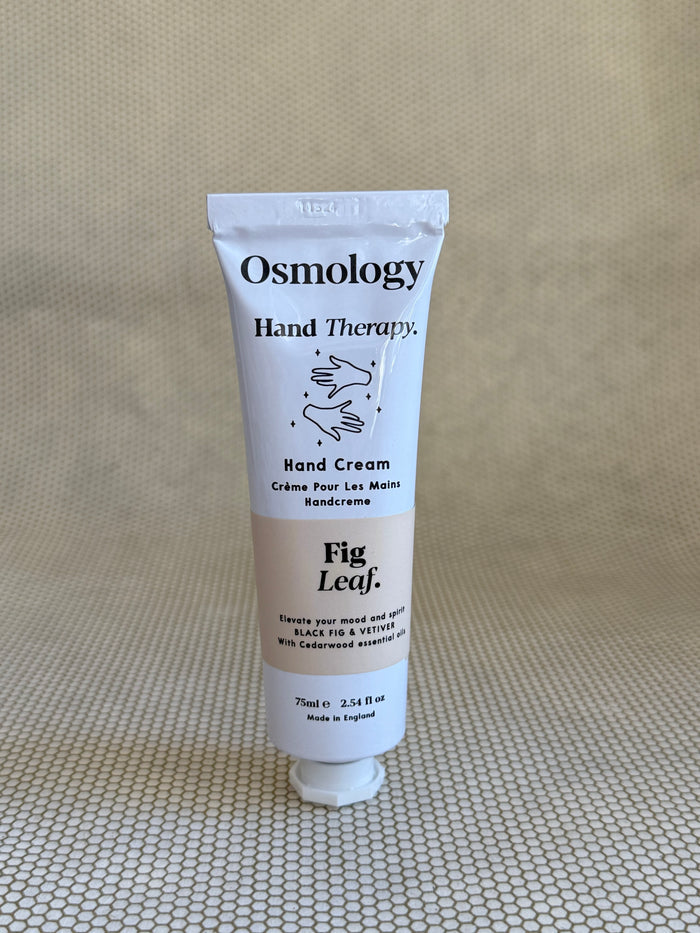 Osmology Fig Leaf hand cream tube on a textured beige surface