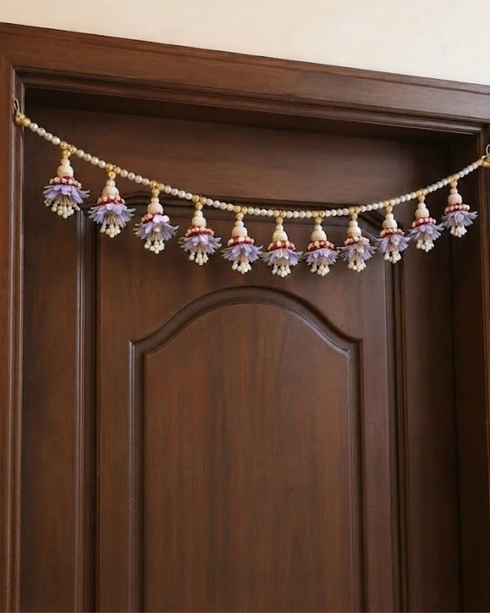 Lavender floral pearl toran garland strung across the top of a wooden door