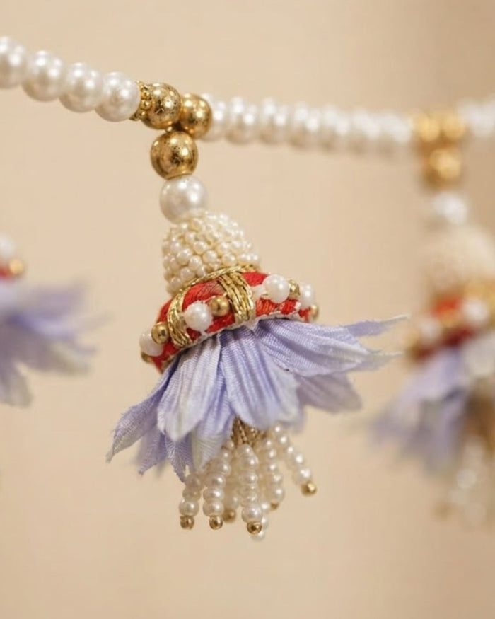 Lavender fabric tassel charm with pearl and gold bead accents on the toran garland