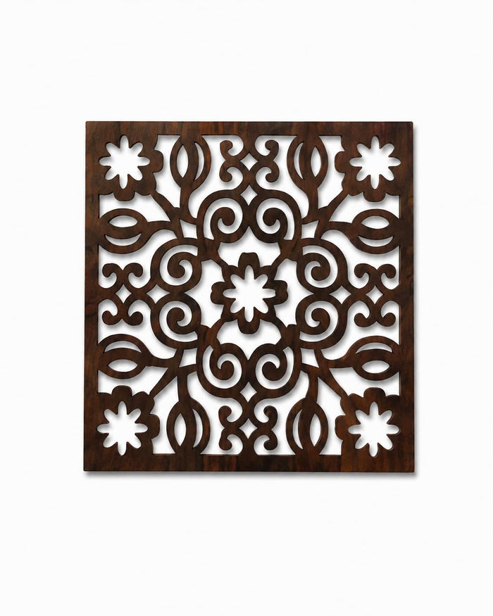 Square dark brown wooden trivet with white floral scroll cutwork and centered flower