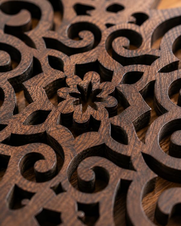 Dark brown wooden trivet close-up with floral scroll cutouts and carved snowflake shapes