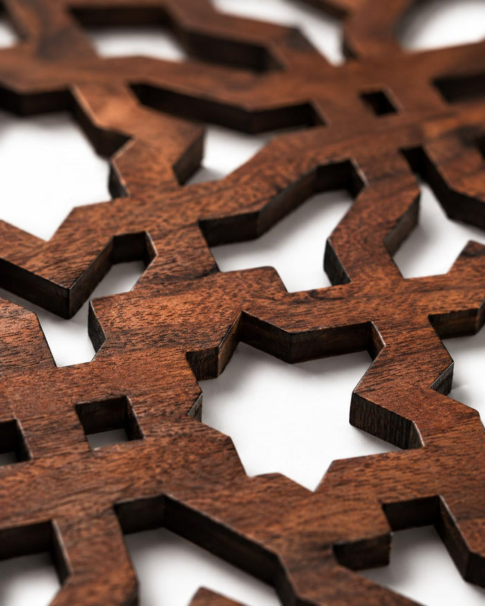 Dark brown wooden trivet close-up of geometric cutout lattice openings