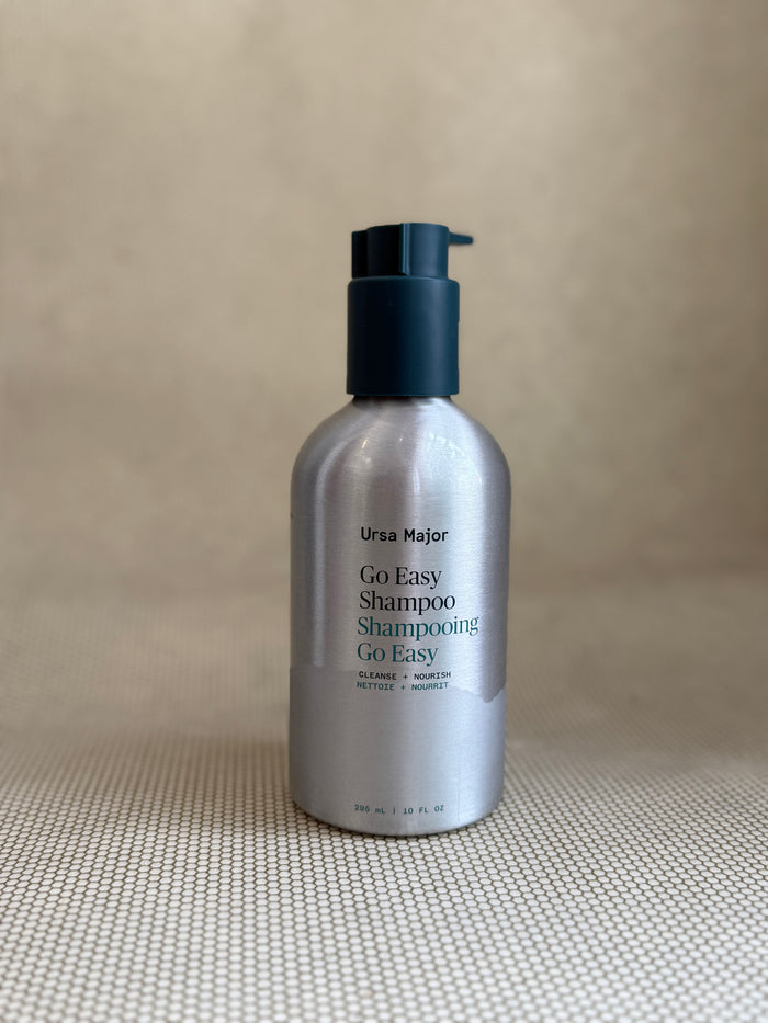 metallic bottle of Ursa Major "go easy" shampoo with pump on neutral background.