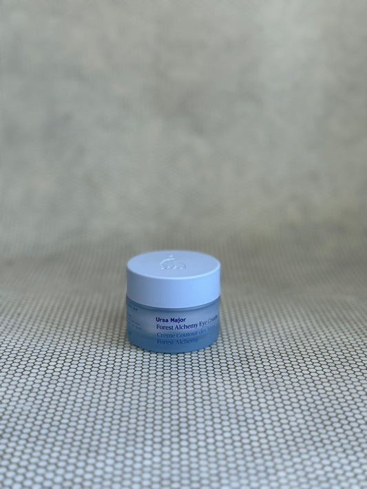 small blue jar of Ursa Major Forest Alchemy Eye Cream in neutral background.